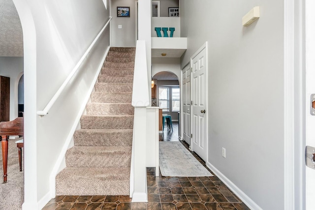 staircase with baseboards and arched walkways