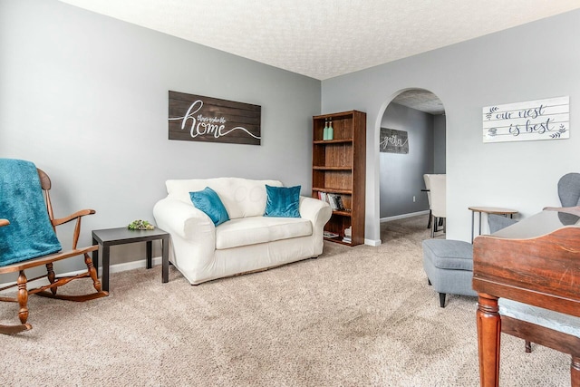 sitting room with arched walkways, a textured ceiling, carpet flooring, and baseboards