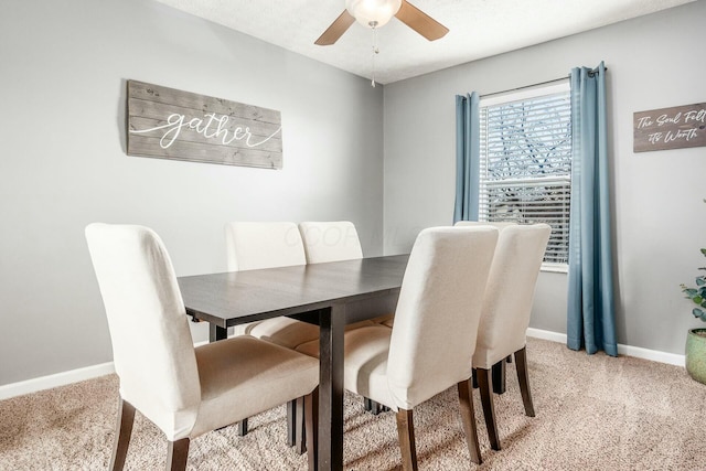 dining area featuring baseboards, a ceiling fan, and light colored carpet