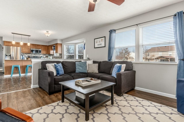 living area with a textured ceiling, light wood-style flooring, and baseboards