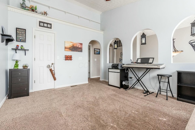 interior space with carpet, baseboards, arched walkways, and a textured ceiling