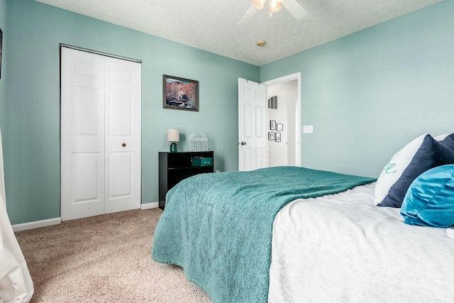 carpeted bedroom with a ceiling fan, a closet, baseboards, and a textured ceiling