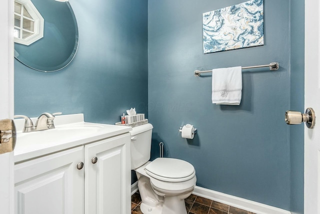 half bathroom with toilet, tile patterned flooring, baseboards, and vanity