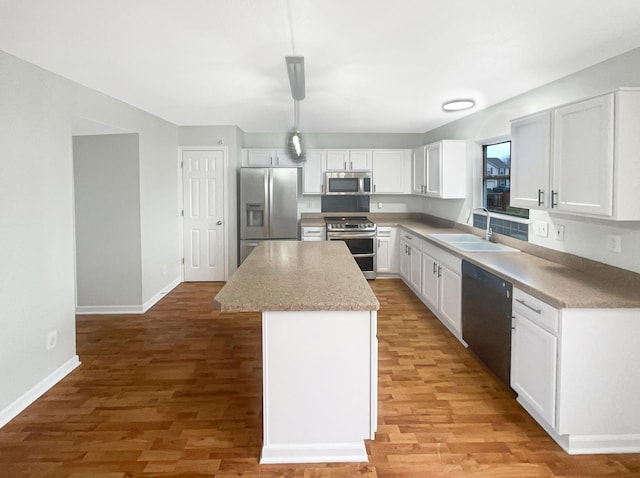 kitchen featuring decorative light fixtures, a kitchen island, sink, appliances with stainless steel finishes, and white cabinets