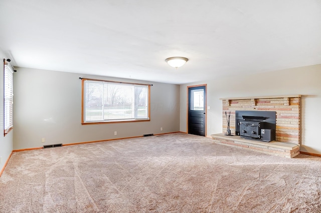 unfurnished living room with carpet floors and a wood stove