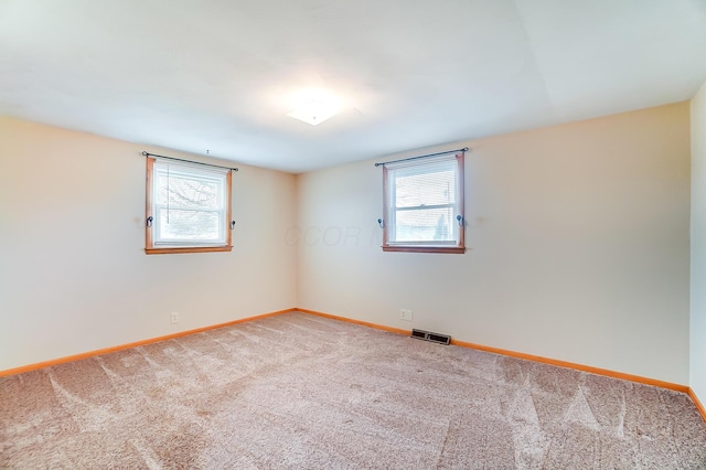 empty room with carpet floors and a wealth of natural light