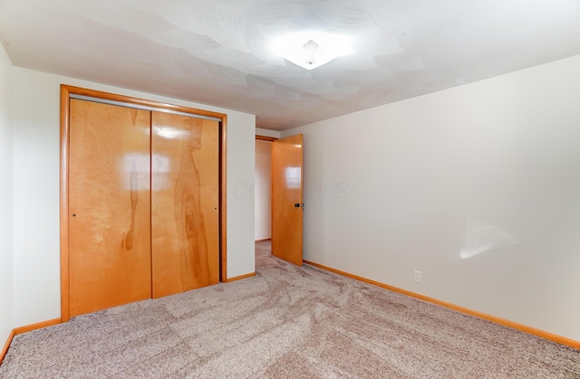 unfurnished bedroom featuring light colored carpet and a closet