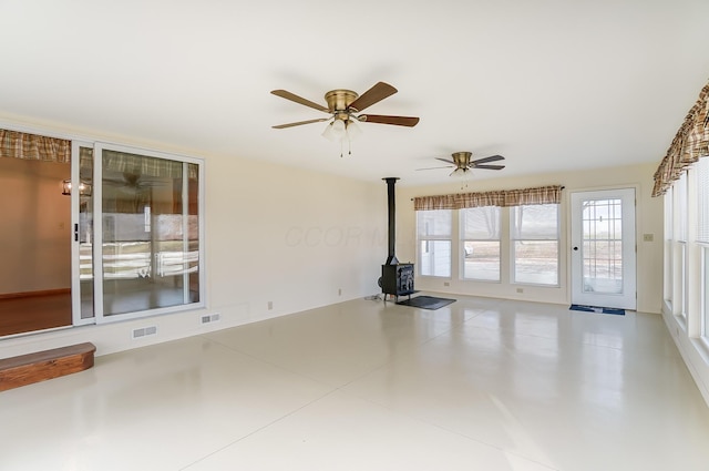 spare room featuring ceiling fan and a wood stove