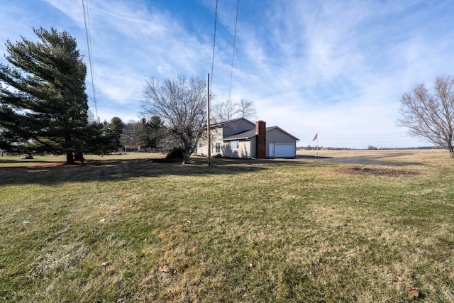 view of yard featuring a rural view and a garage