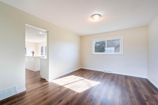 empty room featuring a healthy amount of sunlight and dark hardwood / wood-style floors