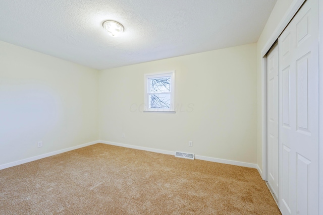 unfurnished bedroom with carpet flooring, a closet, and a textured ceiling