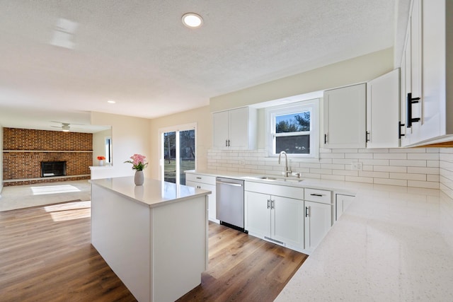 kitchen with sink, white cabinetry, a center island, stainless steel dishwasher, and a healthy amount of sunlight