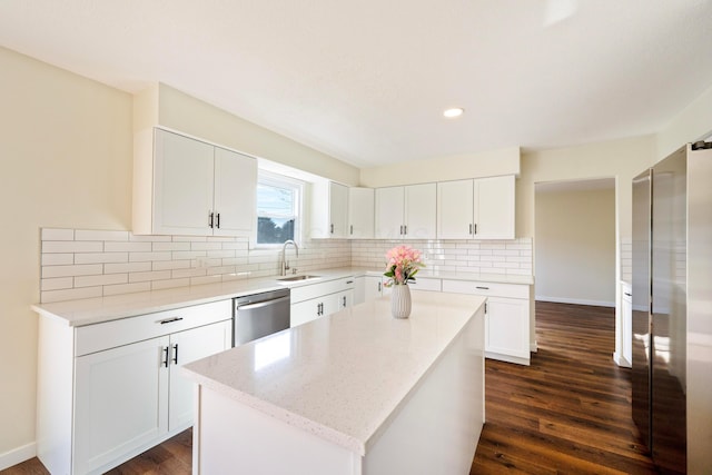 kitchen featuring light stone counters, a center island, appliances with stainless steel finishes, white cabinets, and backsplash