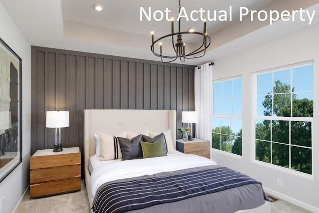 bedroom with a tray ceiling, multiple windows, and a chandelier