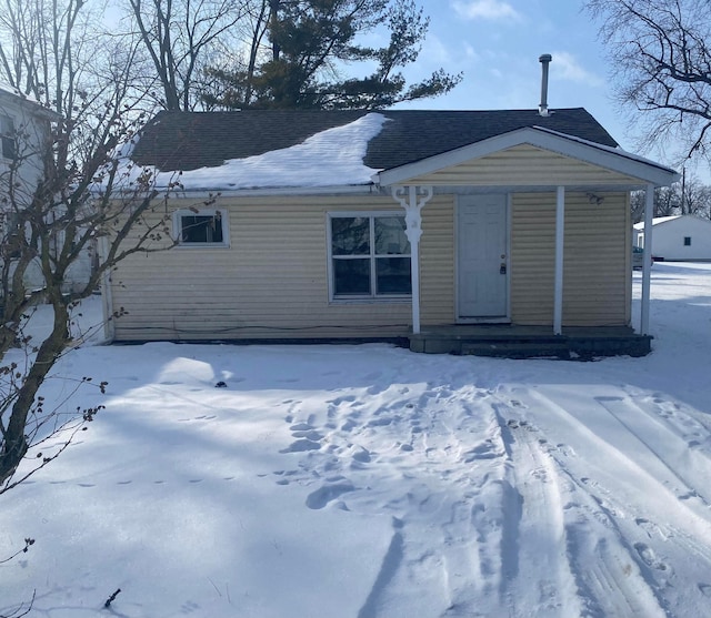 view of front of house featuring a shingled roof, covered porch, and a wall mounted air conditioner