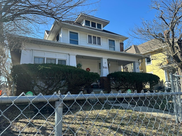 traditional style home with a fenced front yard and a porch