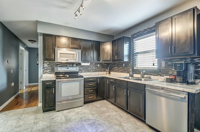 kitchen featuring sink, dark brown cabinets, stainless steel appliances, light stone countertops, and decorative backsplash