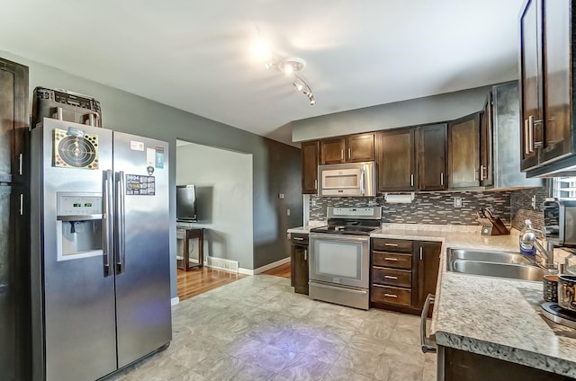 kitchen featuring tasteful backsplash, dark brown cabinetry, stainless steel appliances, and sink