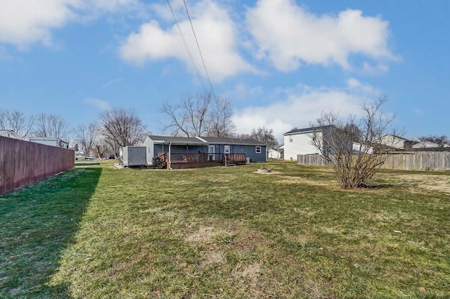 rear view of property featuring a shed, a yard, and a deck