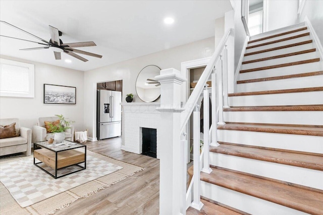 living room featuring light wood-style floors, recessed lighting, ceiling fan, and stairway