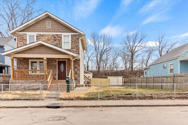 view of front of house featuring covered porch, stone siding, a fenced front yard, and a gate