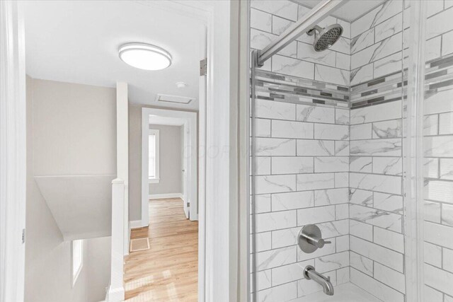 bathroom with visible vents, washtub / shower combination, baseboards, and wood finished floors