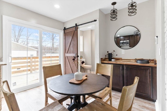 dining space featuring light wood-style flooring and a barn door