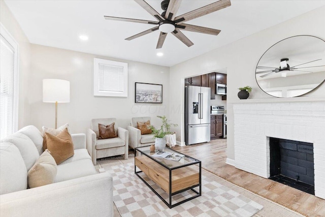 living area featuring light wood finished floors, a fireplace, a ceiling fan, and recessed lighting