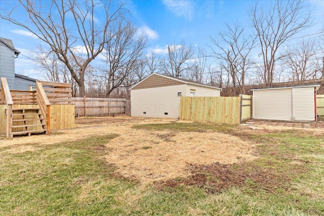 view of yard with an outbuilding, a shed, stairway, and fence