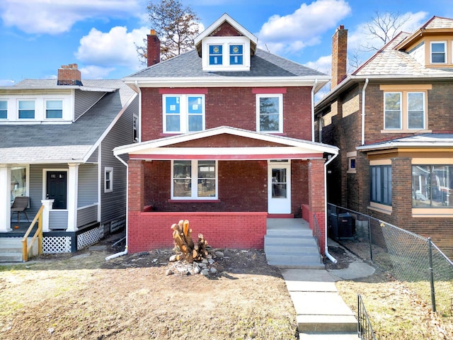 traditional style home with brick siding, a porch, and fence