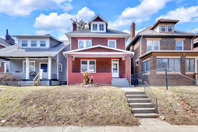 traditional style home featuring covered porch, brick siding, fence, and central AC