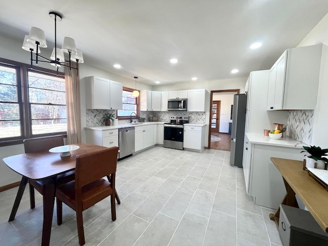 kitchen featuring stainless steel appliances, hanging light fixtures, sink, and white cabinets