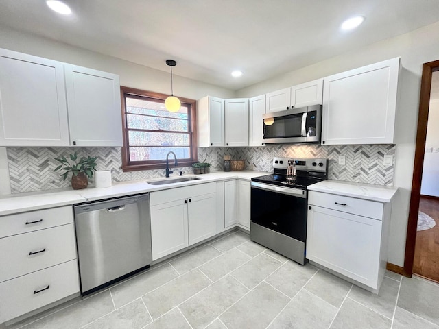 kitchen featuring sink, white cabinetry, decorative light fixtures, appliances with stainless steel finishes, and backsplash