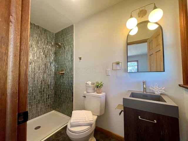 bathroom with a tile shower, vanity, and toilet