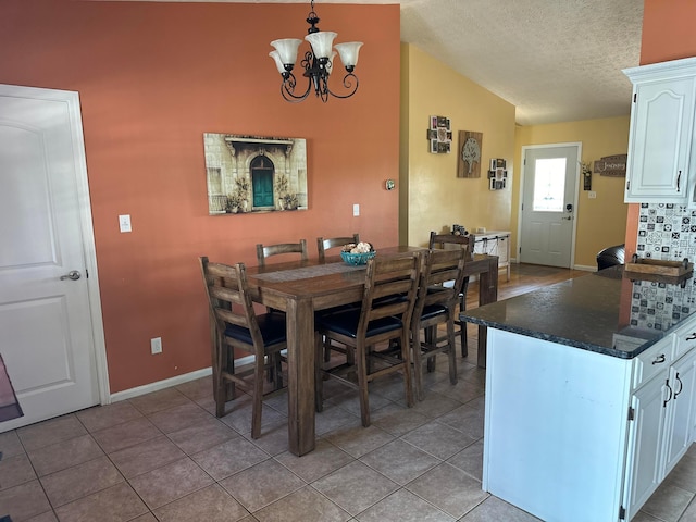 1048 Parkway Dr, Logan, OH 43138 - dining space with light tile patterned floors, vaulted ceiling, a textured ceiling, a chandelier, and baseboards