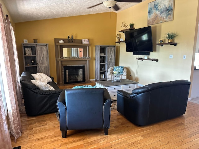 1048 Parkway Dr, Logan, OH 43138 - living room with a ceiling fan, a glass covered fireplace, a textured ceiling, and hardwood / wood-style flooring