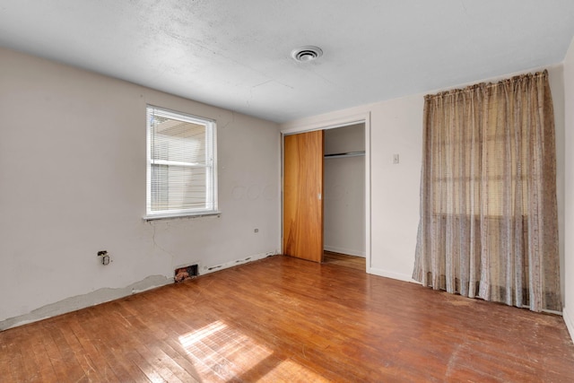 unfurnished bedroom with hardwood / wood-style flooring and a closet