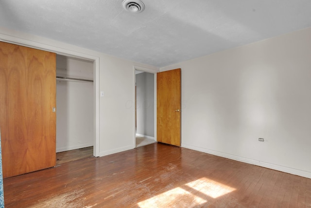 unfurnished bedroom with hardwood / wood-style flooring and a closet