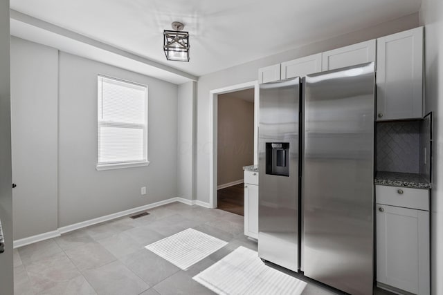 kitchen featuring tasteful backsplash, white cabinets, dark stone counters, and stainless steel fridge with ice dispenser