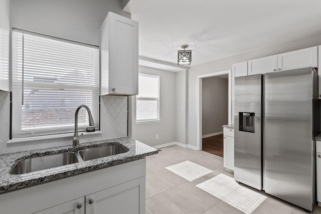 kitchen with white cabinetry, stone countertops, stainless steel fridge, and sink