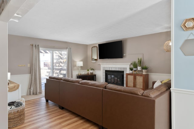 living room featuring a textured ceiling, a tiled fireplace, and light hardwood / wood-style flooring