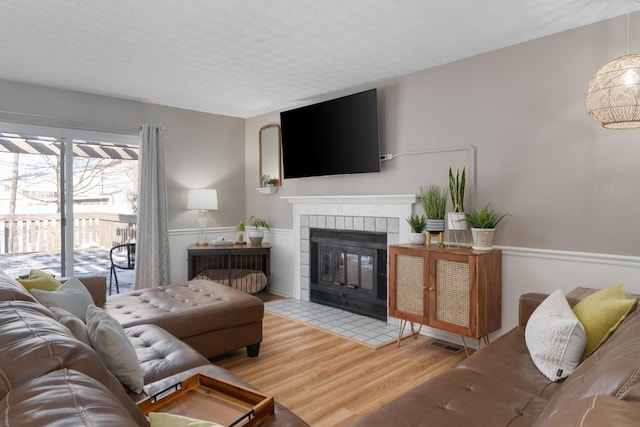 living room featuring a fireplace, light hardwood / wood-style flooring, and a textured ceiling