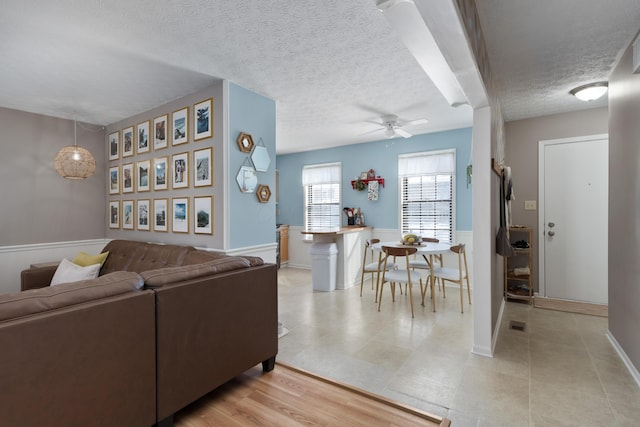 living room featuring light hardwood / wood-style floors, ceiling fan, and a textured ceiling