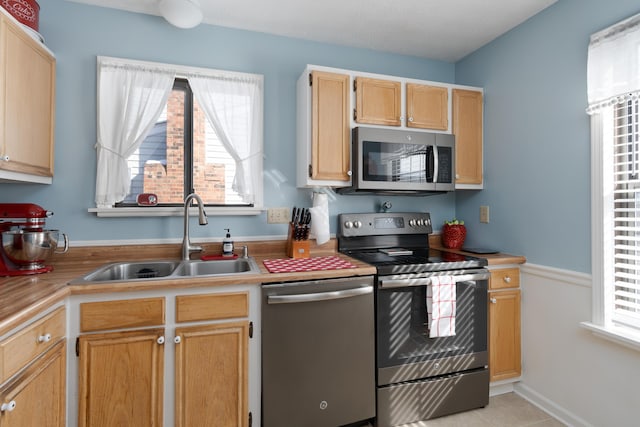 kitchen featuring light tile patterned flooring, appliances with stainless steel finishes, sink, and light brown cabinets