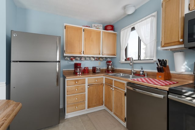 kitchen with appliances with stainless steel finishes, sink, and light tile patterned floors