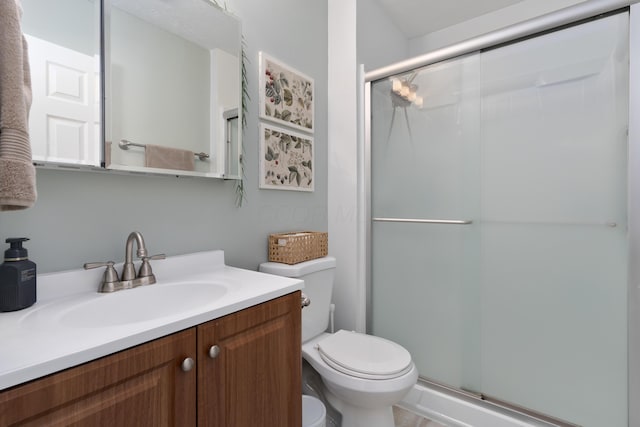 bathroom with vanity, toilet, and a shower with shower door