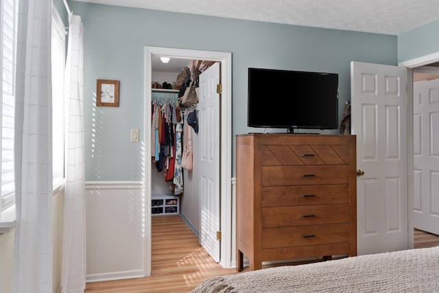 bedroom featuring a textured ceiling, a closet, a walk in closet, and hardwood / wood-style flooring