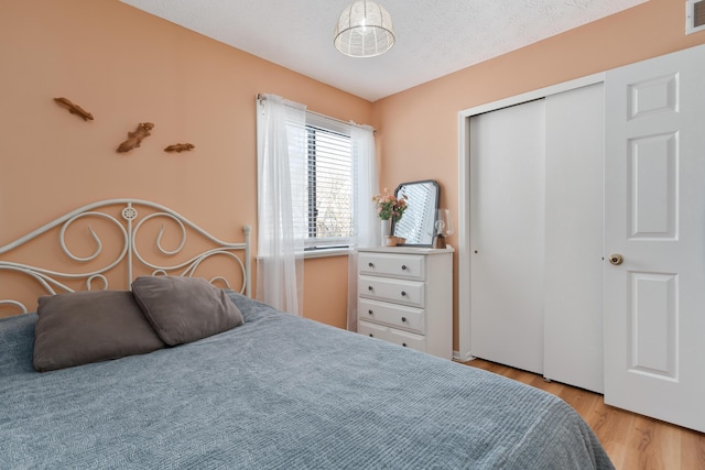 bedroom with light hardwood / wood-style flooring, a textured ceiling, and a closet