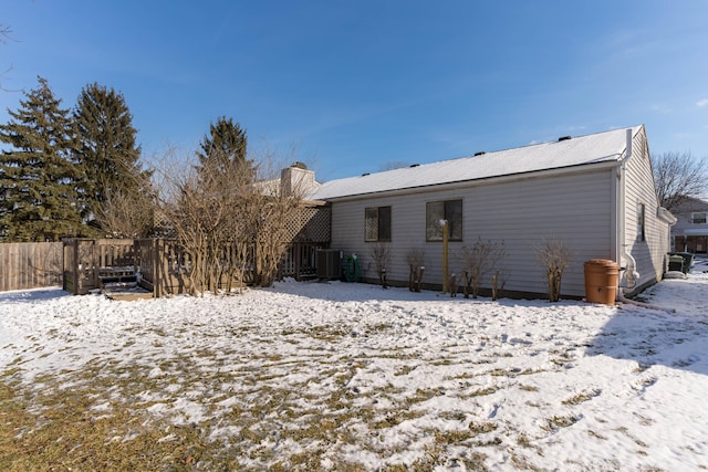 snow covered back of property with central AC