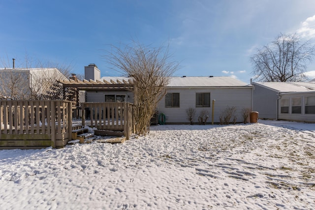 snow covered rear of property with a deck